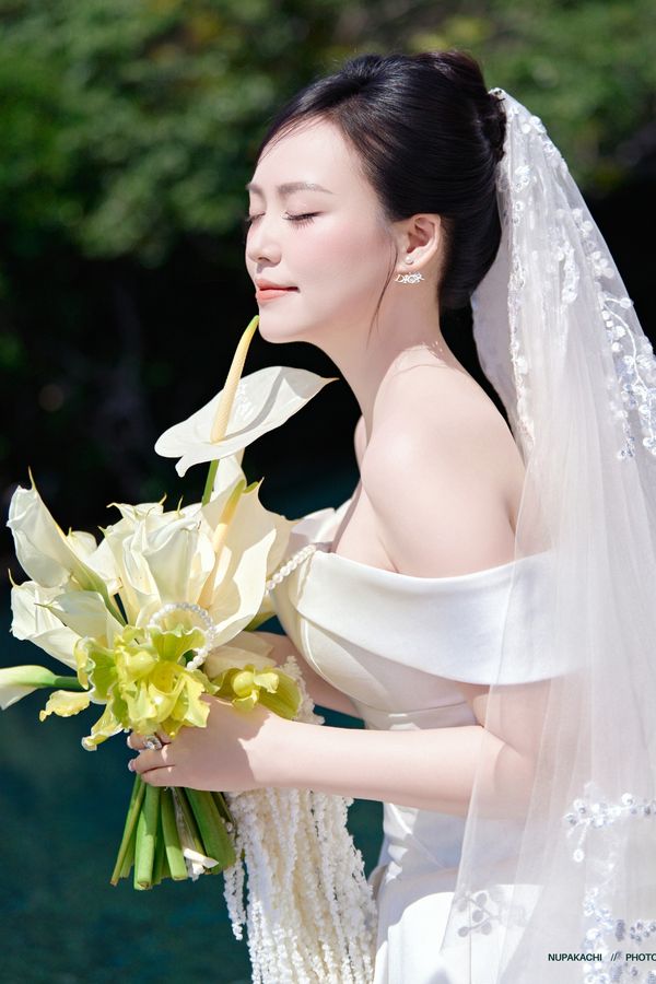 The Bao Loc lace flower edge long wedding veil on a bride holding calla lilies
