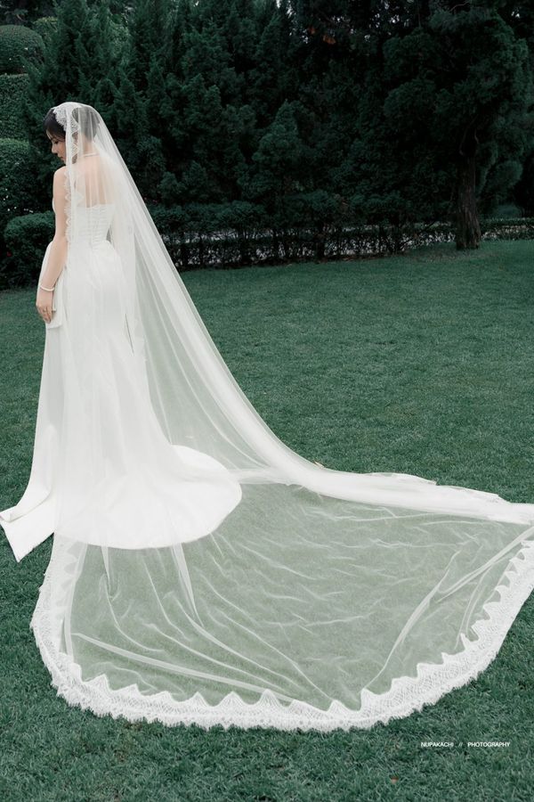 The Da Lat lace edge cathedral wedding veil spread across a garden lawn