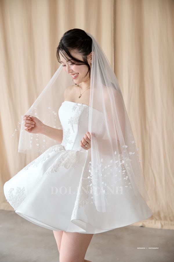 The Mai Chau scattered lace flower fingertip veil with a short wedding dress