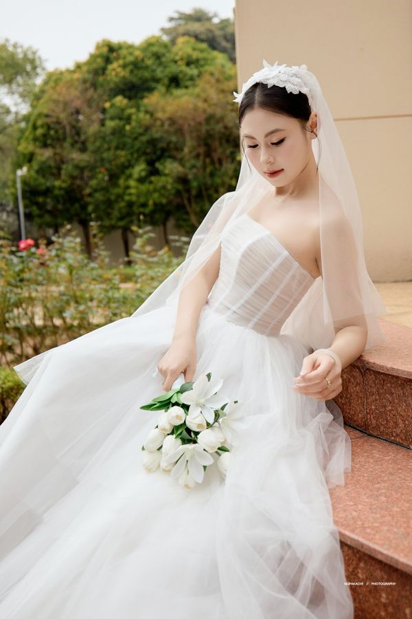 The Phu Quoc flower crown wedding veil on a bride sitting on steps