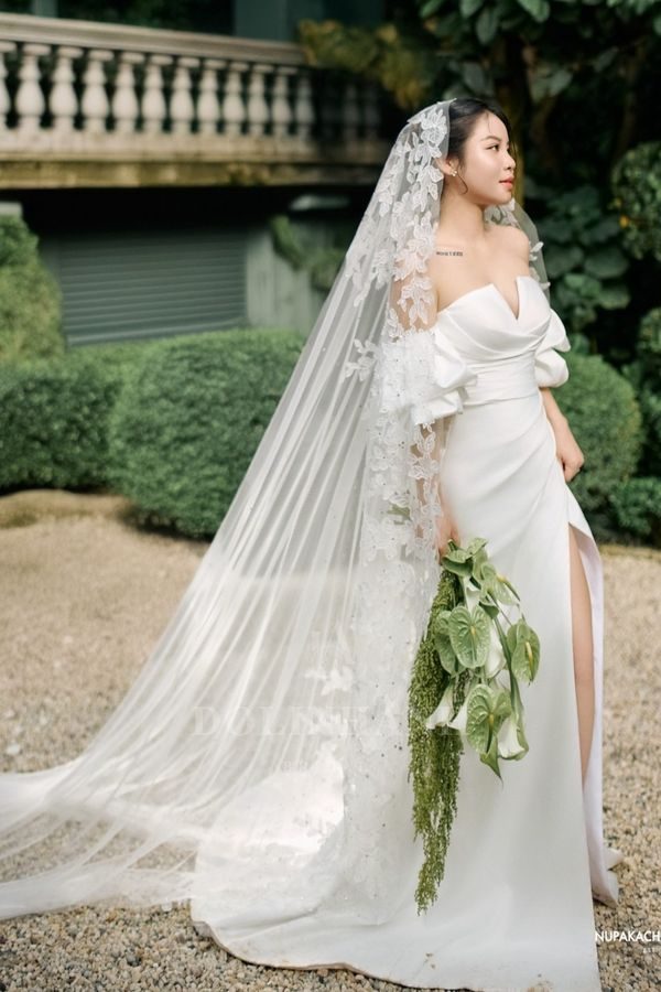 The Trang An lace mantilla cathedral wedding veil in a garden